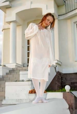 Barely legal redhead Alisabelle poses nude in white stockings outside a house on justmyfans.pics