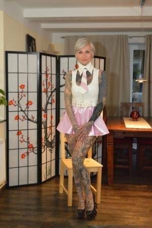 Tattooed platinum blonde Miss Francine models a raincoat over a latex dress on justmyfans.pics